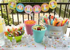 a table topped with lots of cups filled with drinks and candy next to a cake