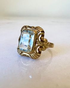 On offer for you is this vintage German ring from the late Art Deco period ~ circa 1930-1940s. It features a very light icy-blue Aquamarine gemstone in a classic ornate high domed setting. The emerald cut gemstone has tested as a natural aquamarine. Modelled in solid 8k yellow gold. Ring face is approx 1.4cm x 1.2cm 🌟Please check out my other listings or follow me as a seller as I have hundreds of beautiful vintage and antique pieces to list :) 🌟 https://jewelledtone.etsy.com ------Item Statis Vintage Signet Ring With Center Stone For Promise, Vintage Gemstone Rings For Collectors, Vintage Collectible Birthstone Ring, Vintage Gemstone Signet Ring For Anniversary, Collectible Vintage Sapphire Ring, Vintage Emerald Cut Birthstone Ring Gift, Vintage Emerald Cut Ring Stamped 14k, Vintage Gemstone Engraved Ring Collectible, Vintage 14k Gold Sapphire Ring