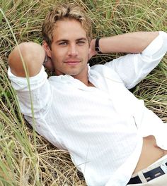 a man laying in the grass with his hands behind his head and looking at the camera