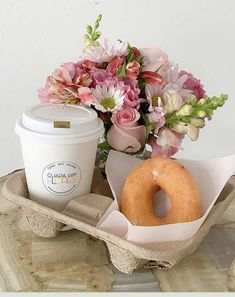 a donut, coffee cup and flowers on a tray