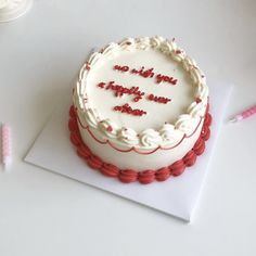 a birthday cake with white frosting and red decorations on top, sitting on a card