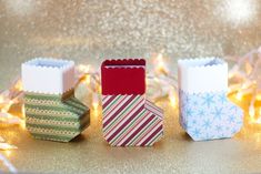 three small gift boxes sitting on top of a table next to christmas lights and decorations