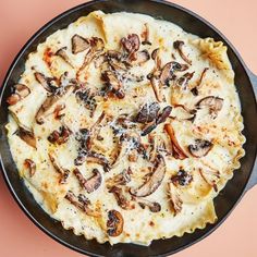 a pizza in a pan with mushrooms on it sitting on top of a pink surface