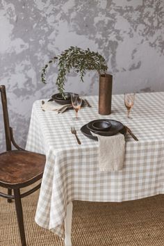 the table is set with two black plates and silverware, one has a potted plant on it