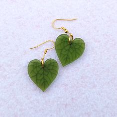 Simple heartleaf earrings. Green heart shaped earrings with engraved leaf veins. Shiny reflective studs that are half an inch and matte drop earrings hanging from a shiny gold leaf stud. These make a great low key Valentine's Day gift, especially if you don't like pink or red! Alternatively, they're for the plant lover in your life. The studs are also a nice unisex gift option. Choose the mini studs or the dangle earrings with default studs, fishhooks, huggies (leverbacks), or clip-ons. Dangle e Fun Jewelry Aesthetic, Cute Drop Earrings, Simple Clay Earrings, Diy Earrings Dangle, Alternative Earrings, Leaf Veins, Plant Earrings, Earrings Hanging, Novelty Earrings