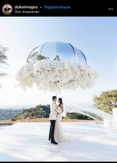 a bride and groom under an umbrella with white flowers