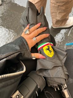 a woman's hand on top of a pair of black gloves with ferrari logo