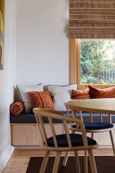 a table and chairs in a room with wooden flooring, white walls and windows