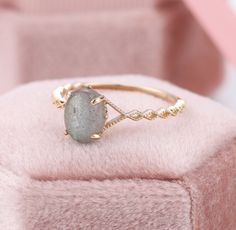 a close up of a ring with a stone on it sitting on a pink cushion