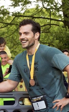 a man is smiling and holding his medal in front of other people at an event