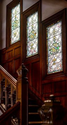 two stained glass windows on the side of a wooden stair case next to a banister