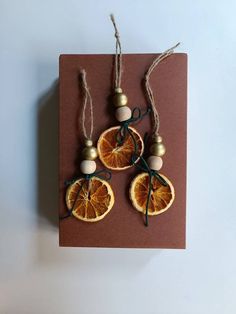 three oranges are tied to twine and placed on a brown piece of paper