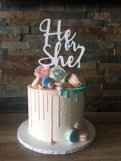 a white cake with pink frosting and blue icing on top that says he or she