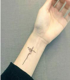 a woman's wrist with a cross and flower tattoo on the left side of her arm