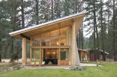 a small cabin in the middle of a forest with lots of grass and trees around it