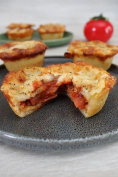 several mini pizzas on a plate with tomatoes in the background