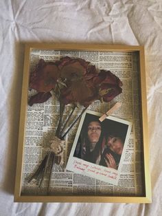 an old book page with flowers on it and a photo pinned to the bottom of one of the pages