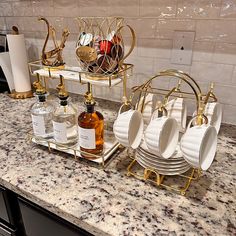 a counter with plates, cups and bottles sitting on it's stand in front of a marble tile backsplash