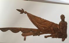 a wooden sculpture sitting on top of a white wall