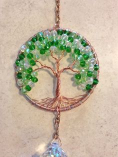 a tree with green and white beads hanging from it's side on a chain