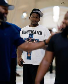 a man in a t - shirt and cap standing next to another man with his hand on his hip