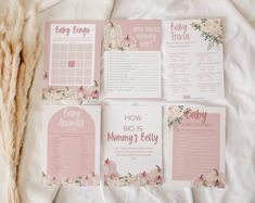 four baby shower games laid out on top of a white sheet with pink flowers and pumpkins