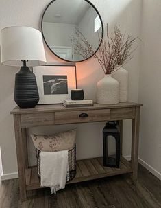 a wooden table topped with a mirror next to a lamp