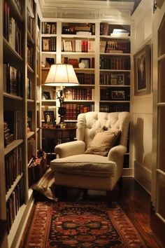 a living room filled with lots of book shelves and a chair next to a lamp