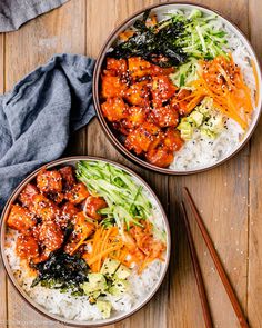 two bowls filled with rice and vegetables on top of a wooden table next to chopsticks