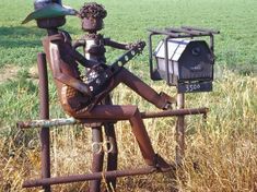 a sculpture of a man sitting on top of a chair in the middle of a field