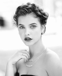 a black and white photo of a woman in a strapless dress with her hand on her shoulder