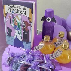 a purple table topped with bottles of liquid next to an open book and some balloons