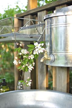 a metal sink sitting next to a potted plant on top of a wooden fence