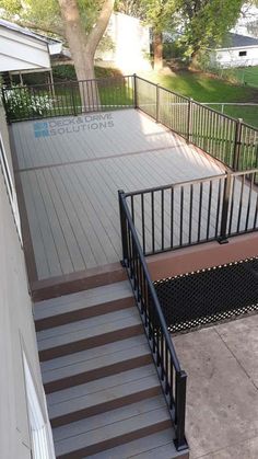 an outdoor deck with stairs and railings next to a tree on the side of a house