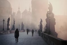 people are walking on a cobblestone walkway in the fog