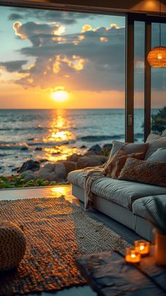 a living room filled with furniture and a view of the ocean at sunset or dawn