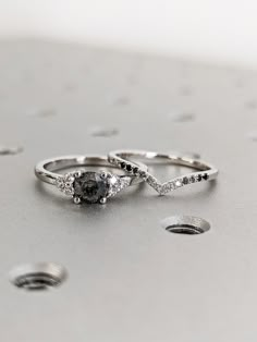 two white gold wedding rings with black and white diamonds on the side, sitting next to each other