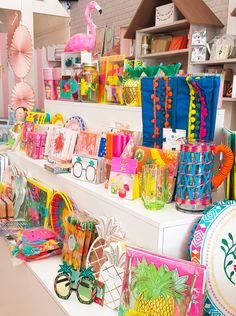 many colorful items are on display in a store with pink flamingos and pineapples