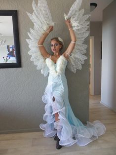 a woman in a dress with angel wings on her head and arms up, posing for the camera