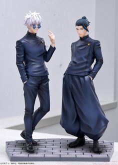 two figurines that are standing next to each other on a table with one holding his hand up