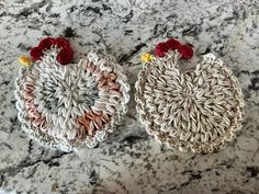 two crocheted roosters sitting on top of a marble counter