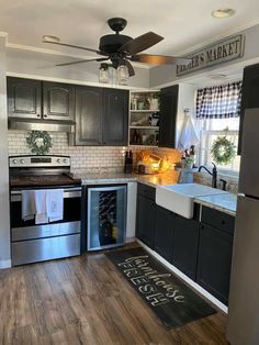 a kitchen with black cabinets and stainless steel appliances is pictured in this image, the ceiling fan is hanging above the sink