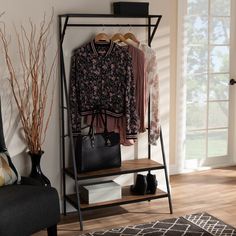 a coat rack with clothes hanging on it in a living room next to a window