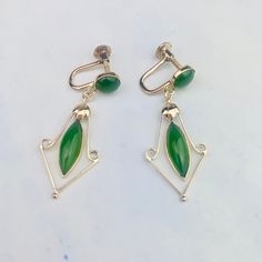 "These beautiful vintage mid-century drop earrings are acquired from an estate auction. The 18K yellow gold heavy earrings feature one round cabochon and one marquise cabochon jade set in bezel setting on each earring and a dangling gold floral frame around the marquise stone. Screw backs tighten securely.  The earrings are 35.6mm (1.40\") long and 14.2mm (0.56\") wide at its widest point, they weigh 3.943 grams. They are marked 18K, and CKP and KPT on the back of the screws, C on one and T on t Oval Art Deco Earrings For Formal Occasions, Art Deco Oval Earrings For Formal Occasions, Retro Dangle Jewelry For Formal Occasions, Formal Oval Art Deco Earrings, Formal Dangle Earrings With Cabochon, Vintage Green Cabochon Earrings, Green Marquise Earrings For Formal Occasions, Retro Dangle Earrings For Formal Occasions, Vintage Dangle Earrings For Formal Occasions