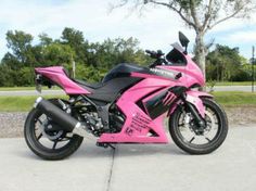 a pink and black motorcycle parked on the street