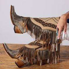 A serving of flowy fringe cascades down the side and the front on this statement making knee-high western boot that is all about the details. Snake Skin printed leather with rivets with an overlay of beige leather on the shaft decorated with hand placed studs. Have fun while you make a statement in every step in these pair of Normandia Fringe. Womenknee Boots With Fringe, Luxury Beige Cowboy Boots With Leather Sole, Luxury Hand-tooled Leather Cowboy Boots, Luxury Hand-tooled Fitted Cowboy Boots, Dingo Fringe Boots, Luxury Formal Desert Boots With Textured Sole, Luxury Leather Hand-tooled Cowboy Boots, Luxury Leather Boots With Tassels, Cute Rodeo Outfits