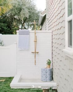 a bathroom with a shower, sink and toilet in the back yard on a sunny day