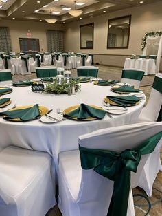 a banquet room set up with white linens and green sashes