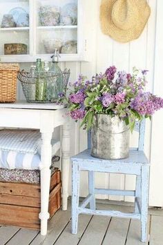 a blue chair sitting on top of a wooden floor next to a vase filled with flowers