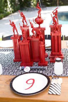 a table topped with red vases and plates